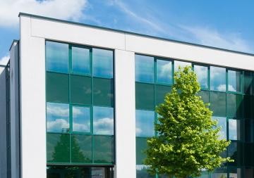 Ein Firmengebäude mit Glasfront; blauer Himmel im Hintergrund.