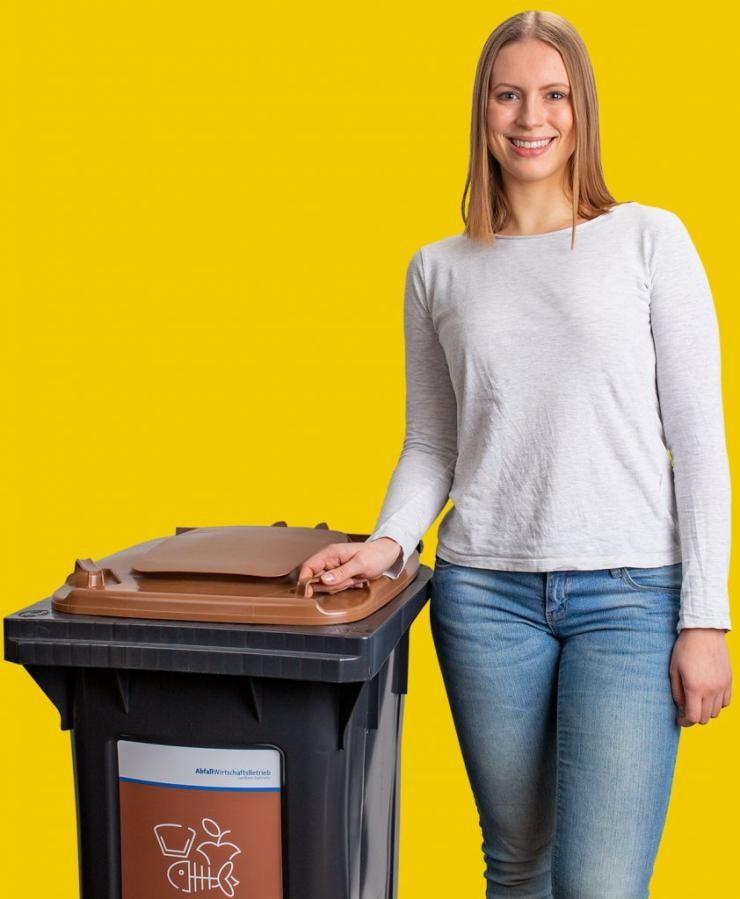 Die Biotonne Eine Frau steht neben der Biotonne und hat eine Hand am Deckel der Tonne.