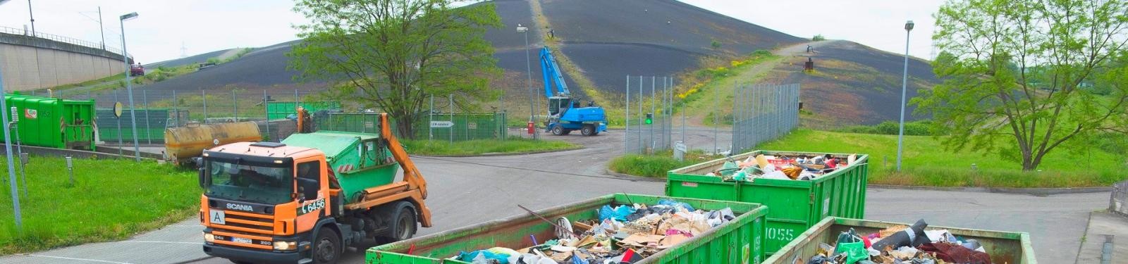 Überregionale Annahmestellen Ein Müllfahrzeug steht auf dem Betriebsgelände einer Deponie, im Vordergrund ein voller Container