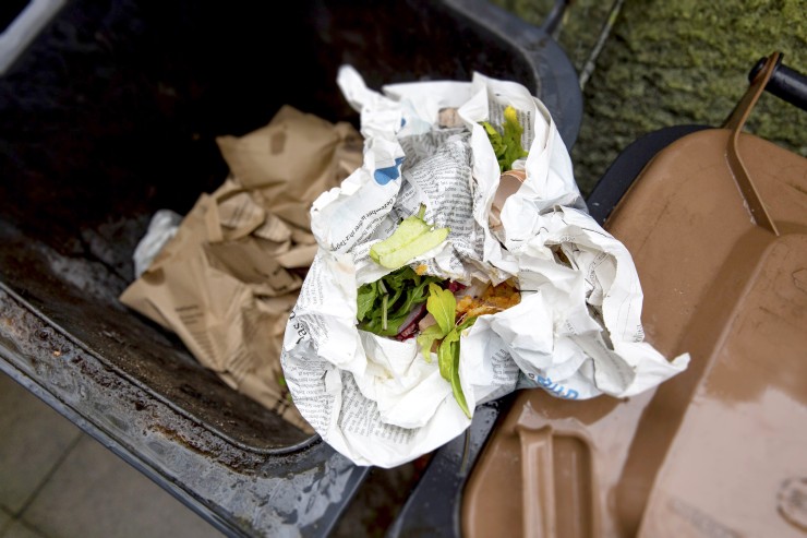 Biotonne im Winter In Papier eingewickelte Bioabfälle in einer Biotonne