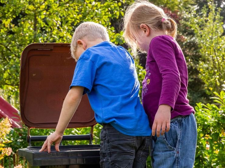 2 kleine Kinder schauen in eine geöffnete Biotonne