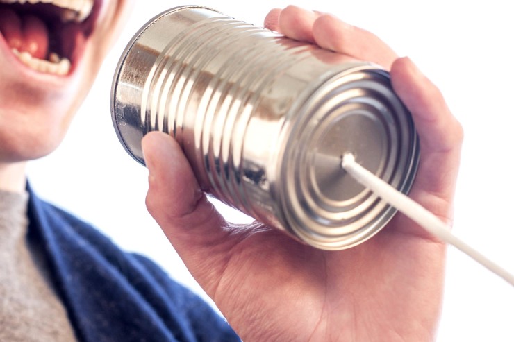 Ein Mann spricht in eine leere Konservendose