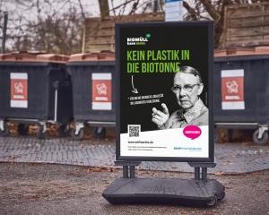 Ein Aufsteller mit #wirfuerbio-Kampagnen-Motiv im Landkreis Karlsruhe vor mehreren Biomabfallcontainern.