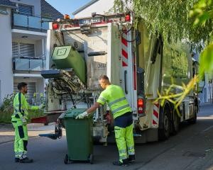 Zwei Müllwerker leeren die Abfalltonnen im Müllfahrzeug.