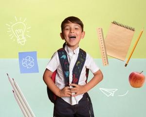Junge lacht, um ihn herum verschiedene nachhaltige Schulmaterialien