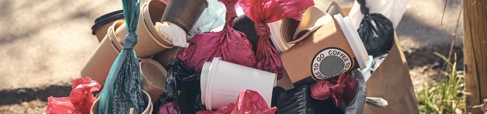 Abfall durch Einweg-to-go-Becher Ein überfüllter Mülleimer, größtenteils gefüllt mit Einwegbechern und Hundekotbeuteln.