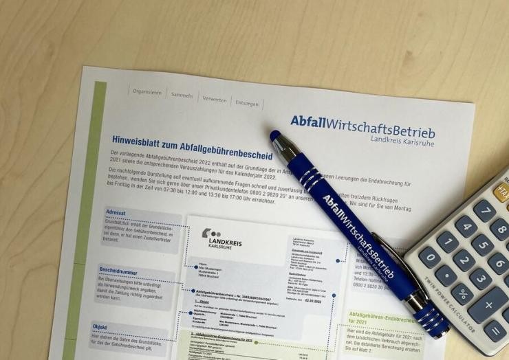 Hinweisblatt Abfallgebührenbescheid mit Kuli und Taschenrechner