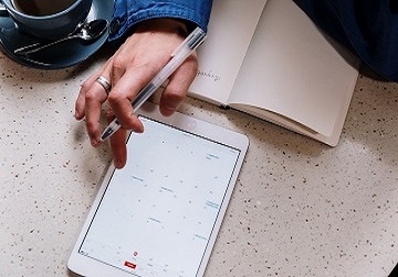Eine Hand  tippt mit dem Finger auf dem Kalender auf einem Tablet