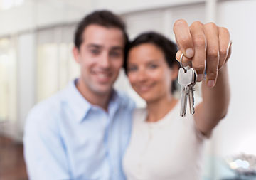 Ein Paar hält einen Schlüssel in Richtung Kamera.